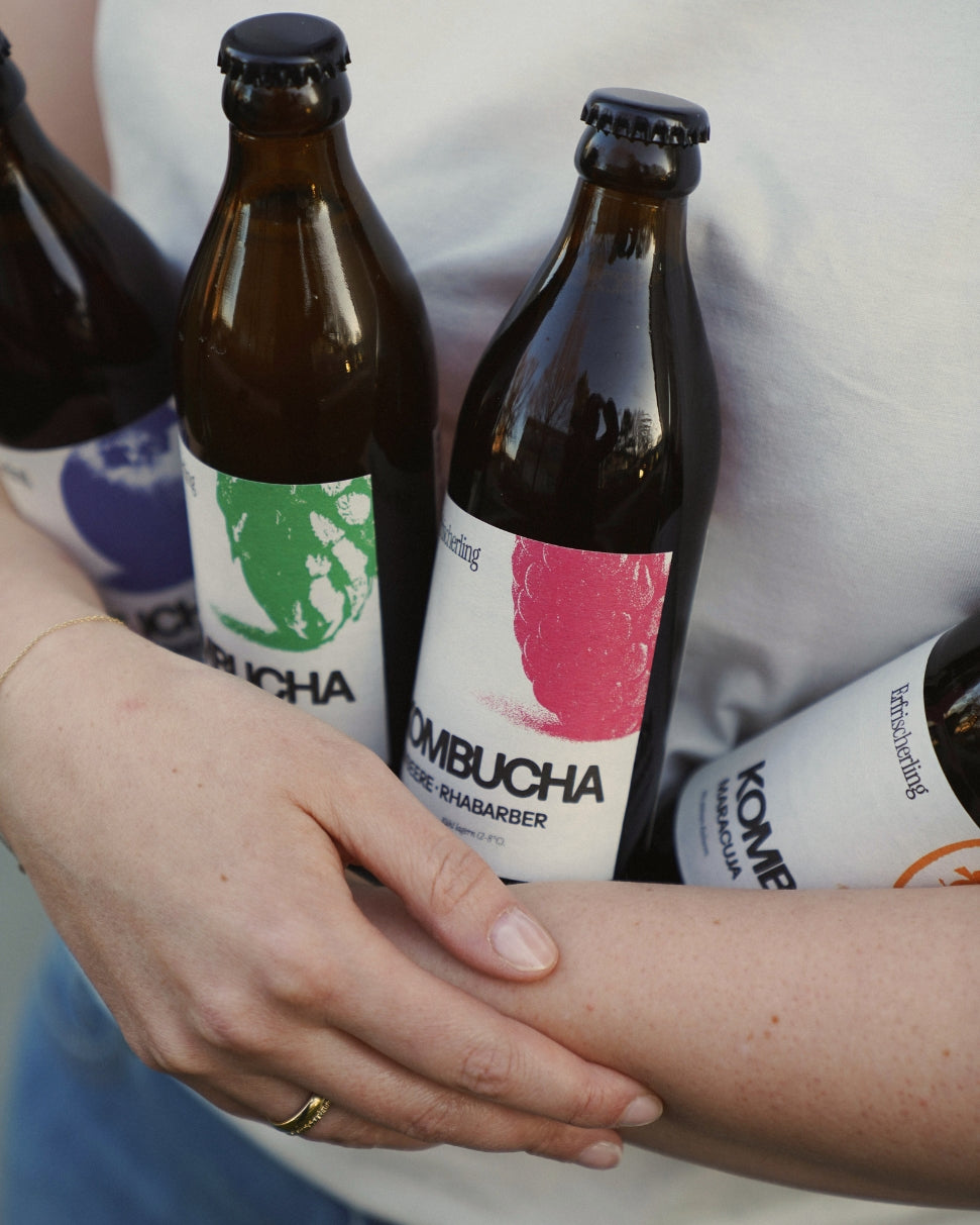 Frau in weißem T-Shirt mit hellblauer Jeans, die alle vier Sorten Erfrischerling in ihrem Arm hält